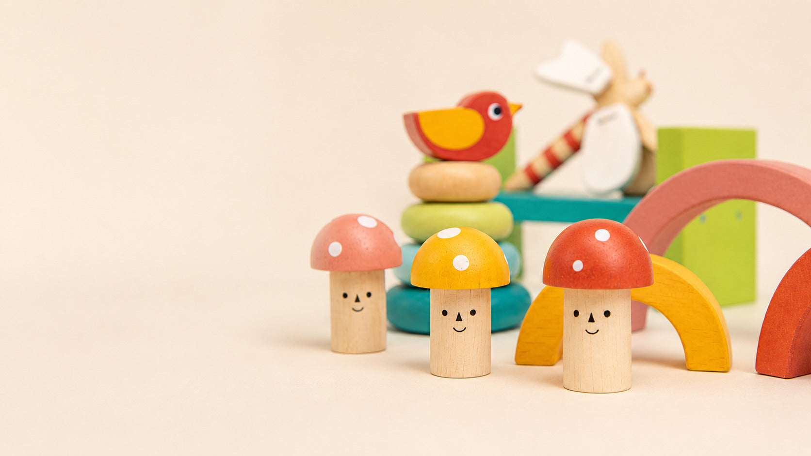 Colorful wooden toy mushrooms with smiling faces on a beige background